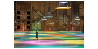 Person pictured on fluorescently lit floor with low handing lights above