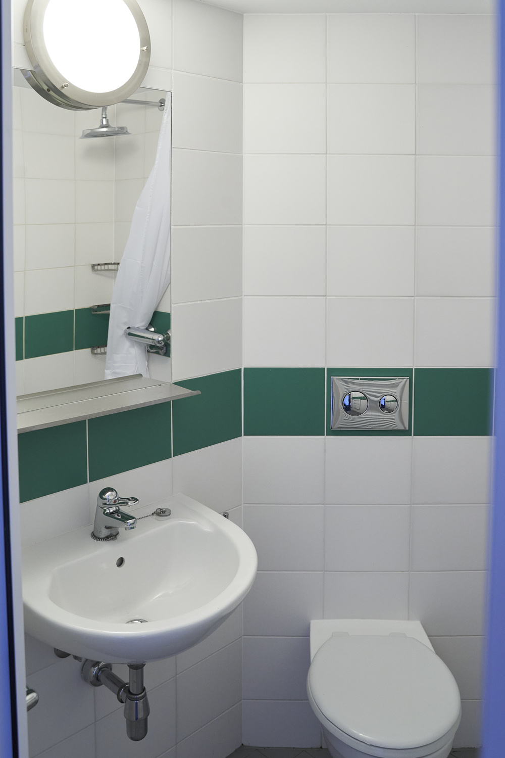 bathroom with toilet and sink with green and white tiles