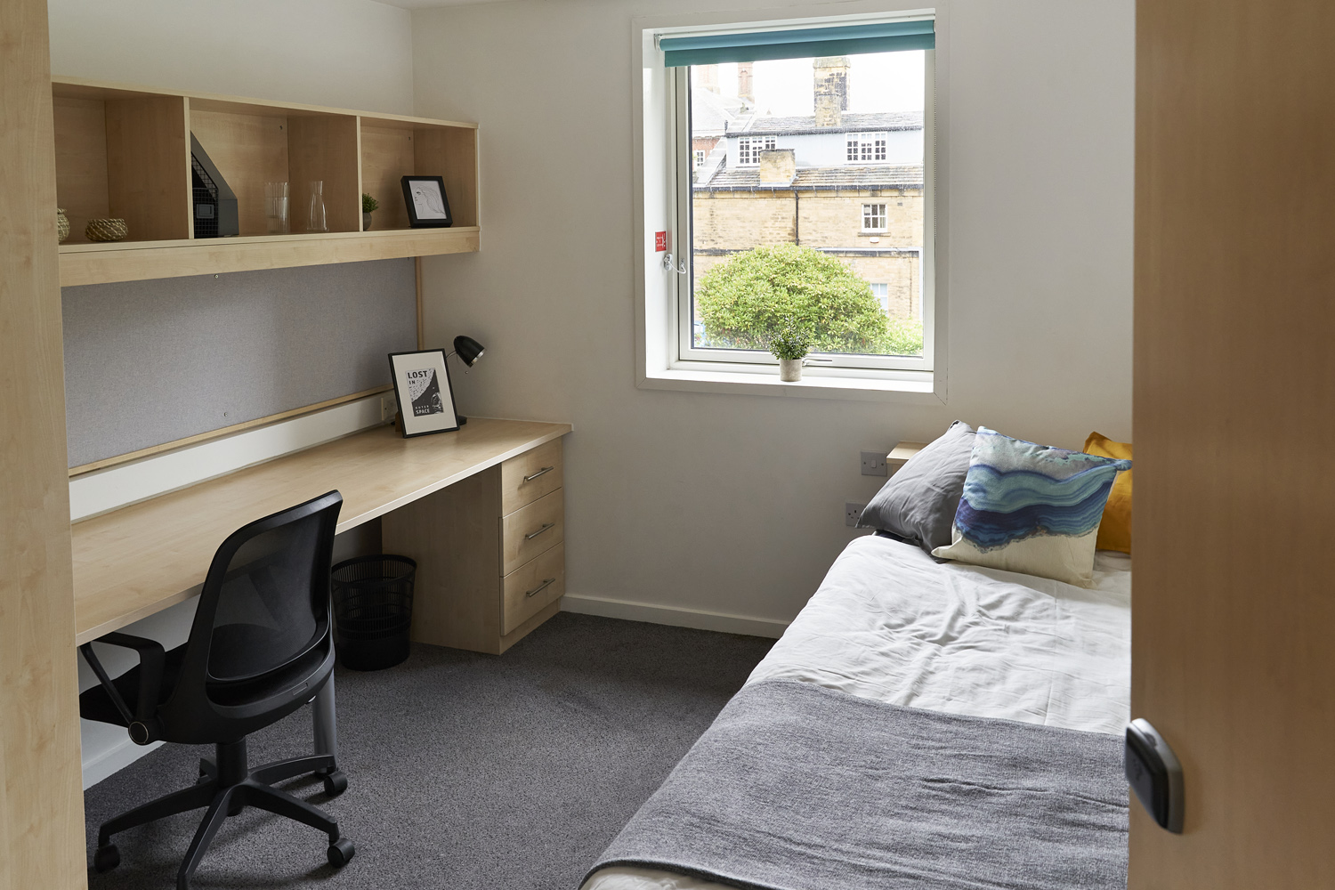 View of student room desk and bed from hallway