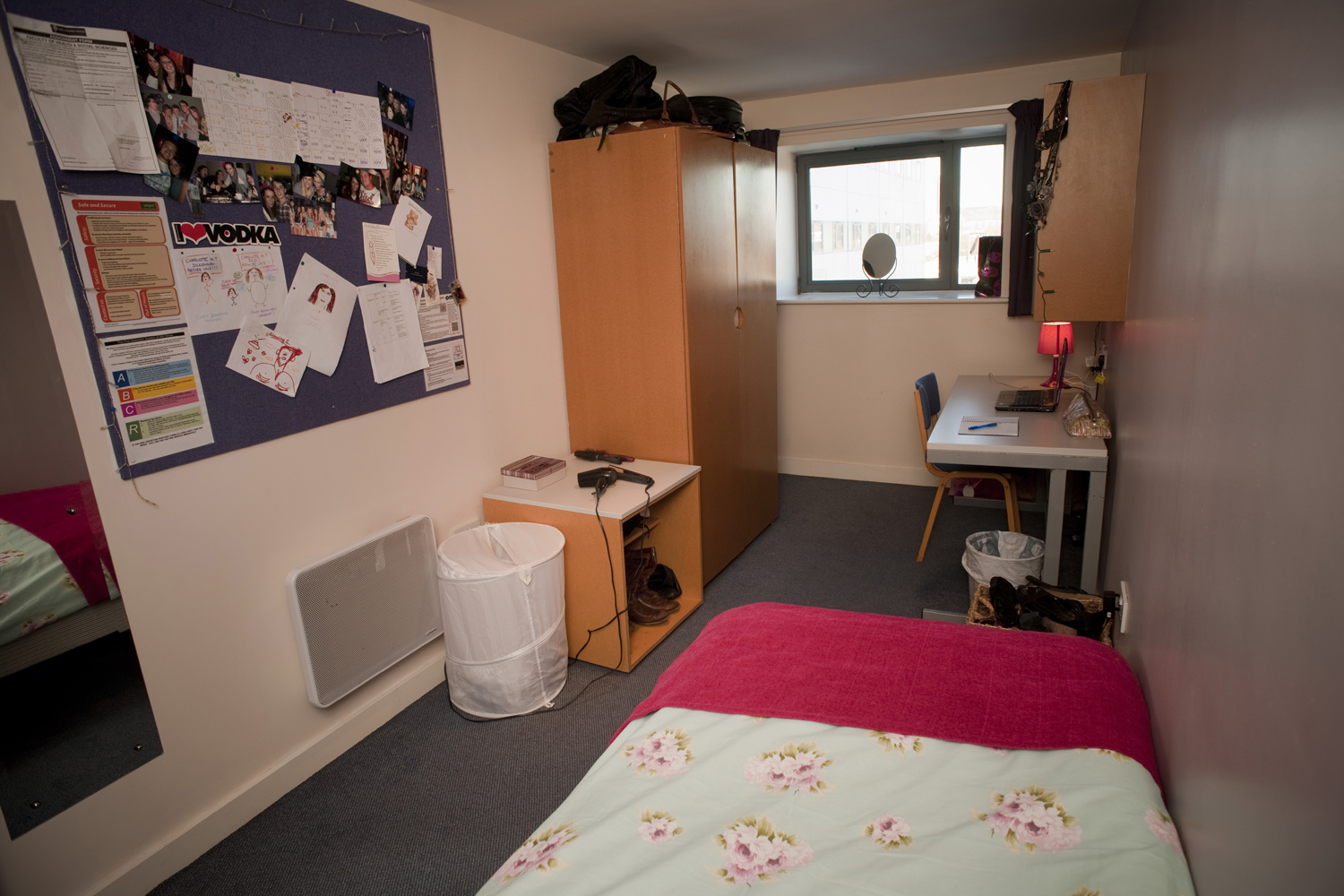 View from a single bed with a desk on the right and wardrobe on the left 