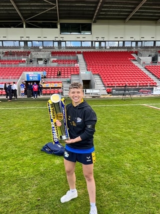 Leeds Beckett alumni Beth Vickers stood outside holding a trophy