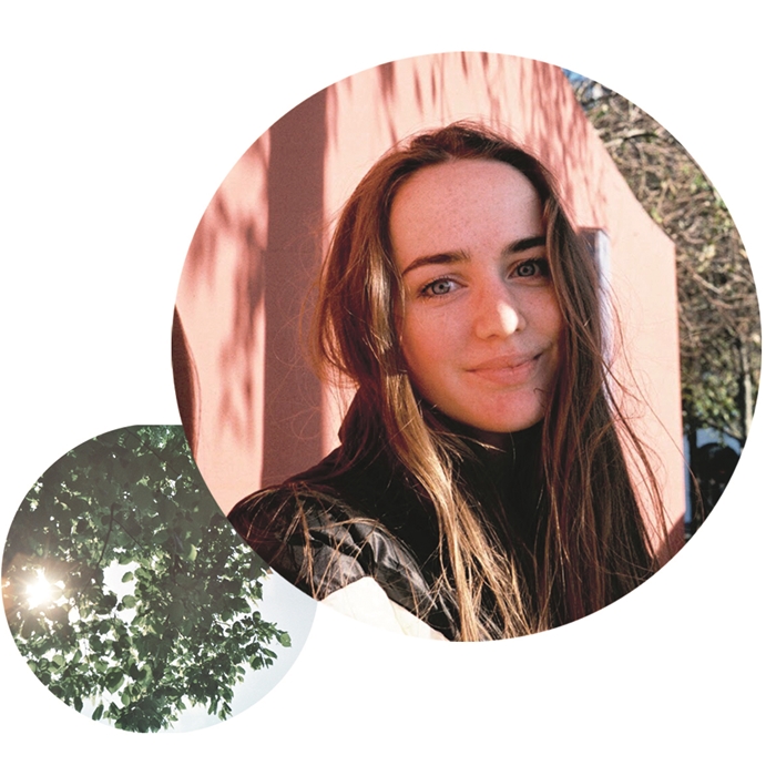 Young white woman with dark brown hair, stood in front of a pink building