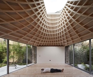 Man laying beneath a geometric, sculptural ceiling