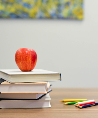 image of apple on top of books and pencils