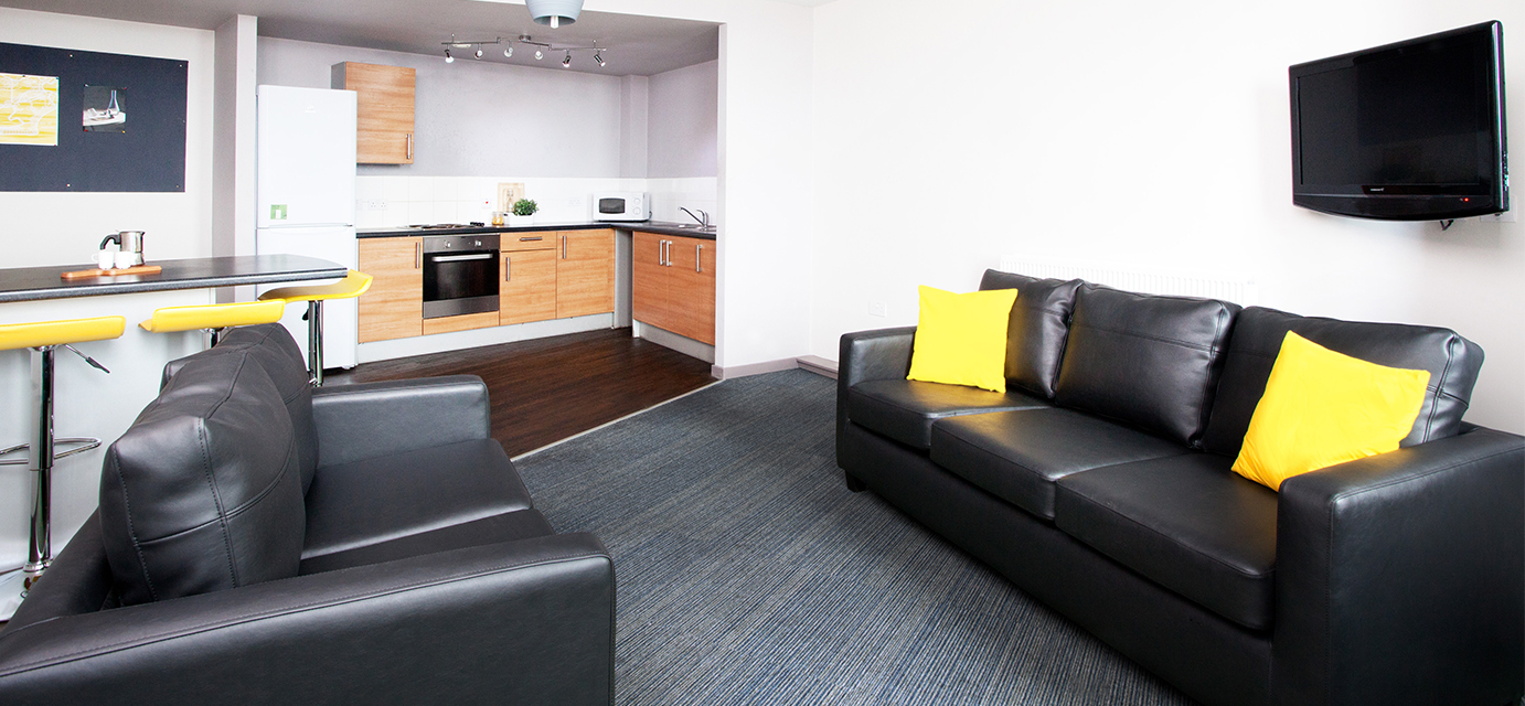 Living space at Broadcasting Tower, sofas and a breakfast bar with stools are in the foreground and kitchen in the background