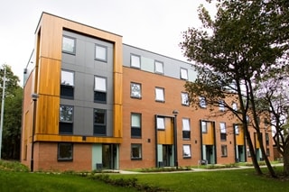 Carnegie Village exterior, brown and dark grey building with some trees in front