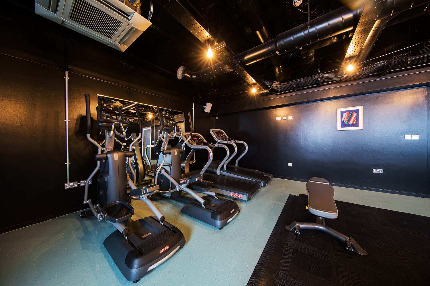 A bank of exercise machines against a black wall