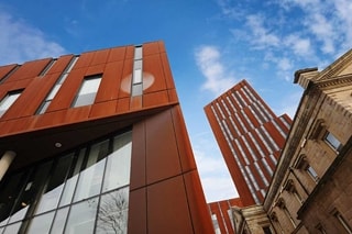 Ground view of Broadcasting Place with blue skies and white clouds above.