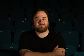 Male in black t-shirt folding his arms
